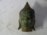 une petite statue représentant une tête de Bouddha posée sur une table