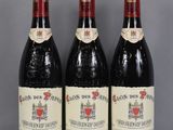 three bottles of red wine sit on a glass table