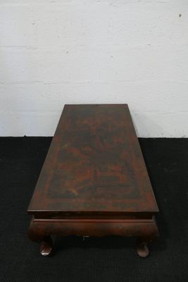 une table basse ancienne en bois à deux pieds, posée sur un tapis noir