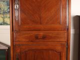 a tall wooden cabinet with a door on top of it