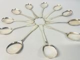 six silver spoons arranged in a circle on a white surface