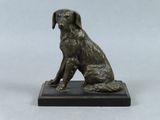 statue en bronze représentant un chien assis sur un socle noir