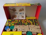 a red box with wooden toys in it on a white surface