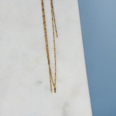 un gros plan d'un collier en or posé sur une surface en marbre