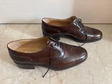 pair of brown leather shoes with laces on them on a marble floor