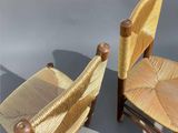 two wooden chairs with wicker seats sit next to each other