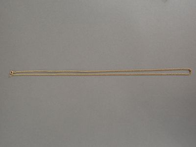 une main tenant un collier en or dont pend une longue chaîne