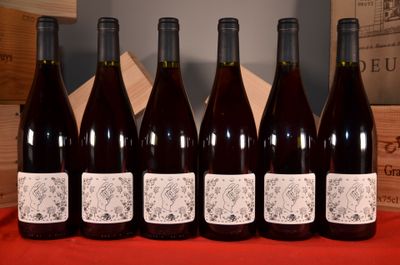 six bottles of red wine are lined up on a table