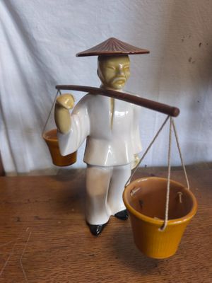 une figurine représentant un homme portant un panier de provisions sur l'épaule