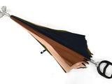 un parapluie noir et marron et une paire de ciseaux posés sur une surface blanche