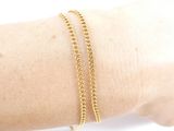 someone is wearing a gold bracelet with a chain on their arm