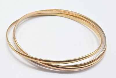 deux bracelets « bang bang » en or posés sur une surface blanche