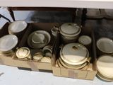 une boîte contenant de nombreux plats et bols blancs et dorés