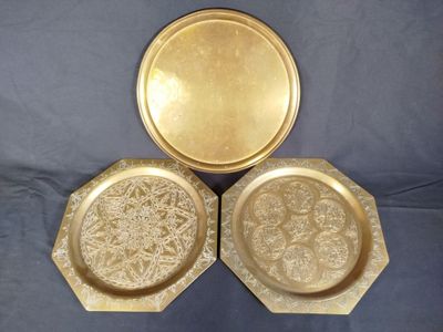 three gold plates with a flower design on them on a blue background