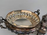 a silver plate with a silver lid and a silver pepper shaker