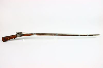 un vieux pistolet avec une poignée en bois sur une surface blanche