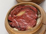 a wooden container with a meat in it on a table