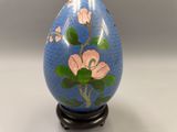 a blue vase with pink flowers on it on a stand