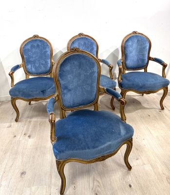 Quatre chaises bleues sont posées sur un parquet dans une pièce