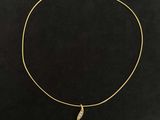 a gold necklace with a leaf charm on a black background