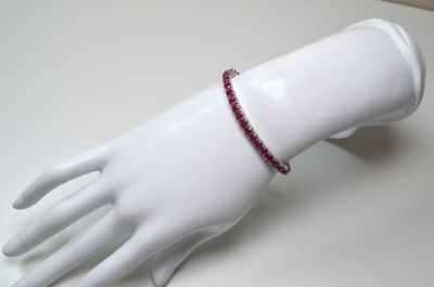 a white mannequin hand with a red bracelet on it
