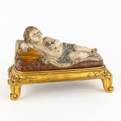 une statue représentant un homme allongé sur un lit sur lequel se trouve un bébé
