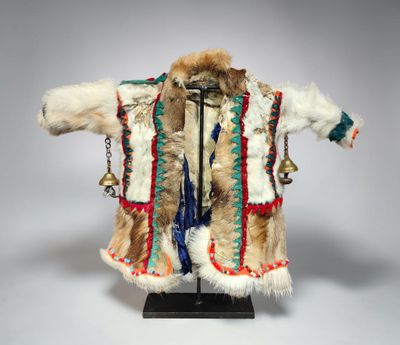 a white and brown fur coat with a bell hanging from it ' s neck