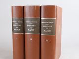 three brown books sitting on top of each other on a white surface