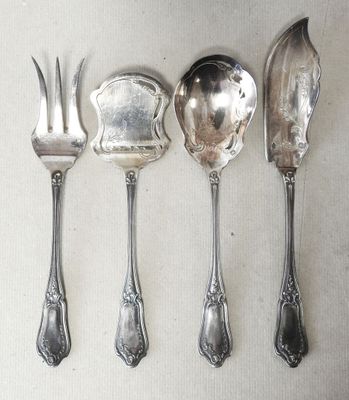 four spoons and a fork are lined up on a table