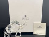 figurine en cristal représentant un chameau posée sur une table noire, à côté d'une boîte blanche