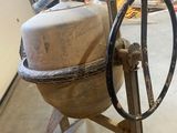 a cement mixer sitting in a garage with a wheel on it