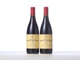 two bottles of red wine sitting on top of a table