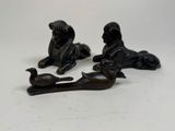 three bronze figurines of animals and a bird on a white surface