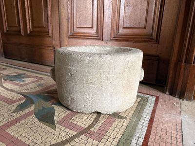 a stone planter sitting on the floor in front of a wooden door