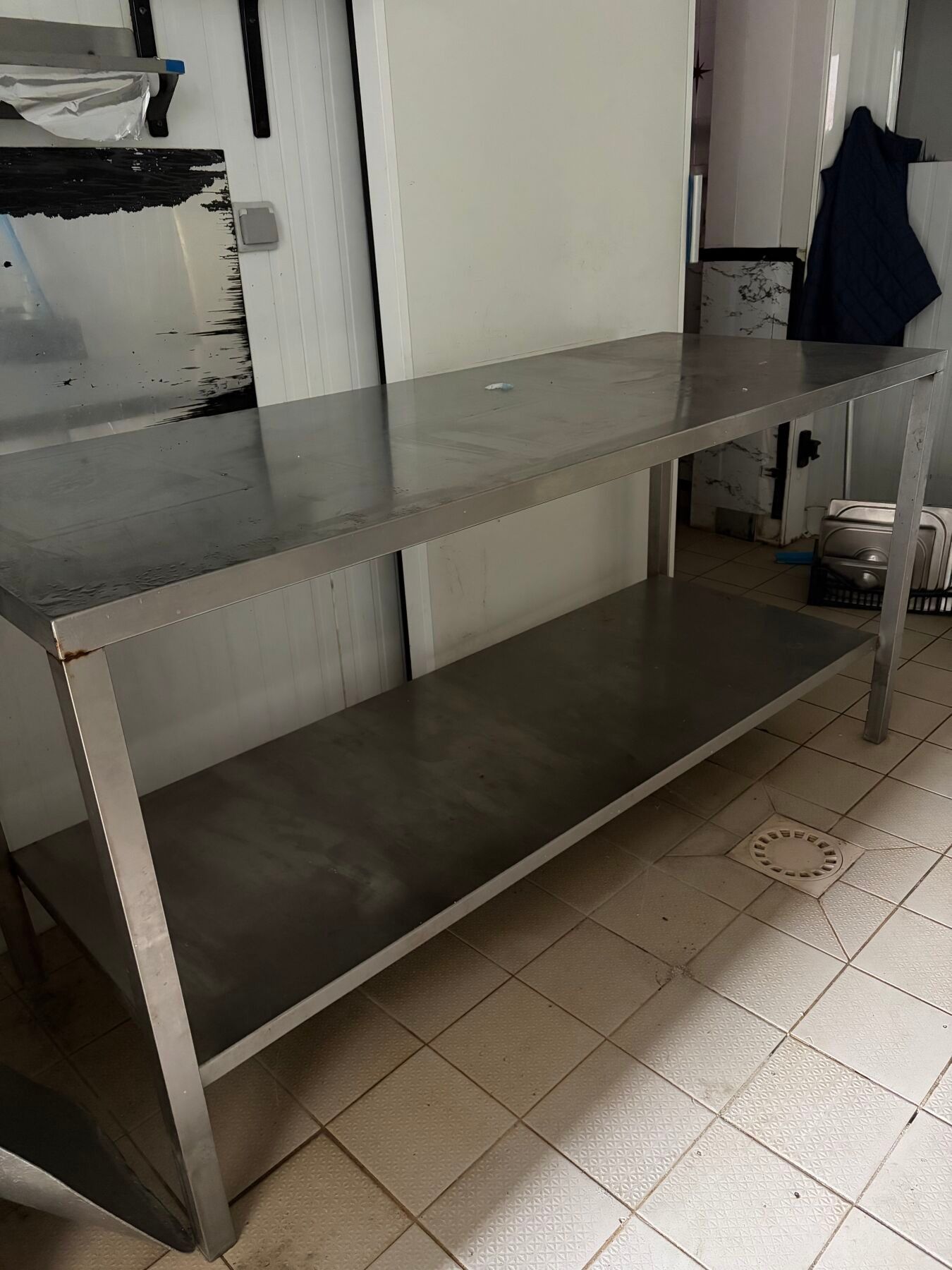 Une table inox avec tablette entre jambe.