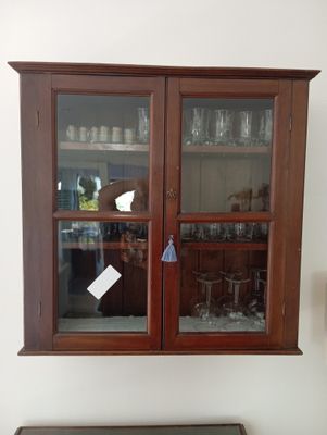 une armoire avec une porte vitrée et une étagère sur laquelle sont posés des verres à vin