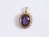 a close up of a purple stone pendant on a white surface