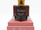 un flacon de parfum posé sur une boîte rose