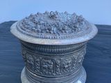 un plat ancien en argent contenant des raisins, posé sur une table noire