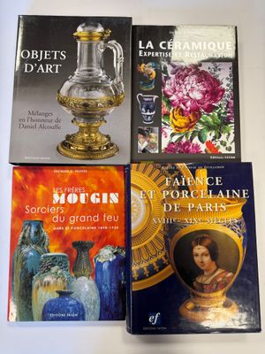 quatre livres posés sur une table, sur laquelle se trouvent également des vases et des tableaux