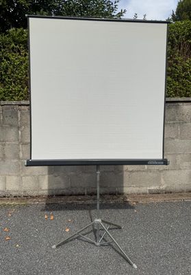 un écran de projection monté sur un trépied devant un mur de pierre