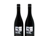two bottles of wine sitting next to each other on a white surface