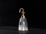 a small glass bottle with a brass handle on a black surface