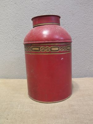 a red vase sitting on a table with a white wall in the background