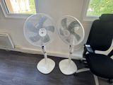 two chairs and a fan in the corner of a room