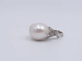 a close up of a pearl and diamond ring on a white surface