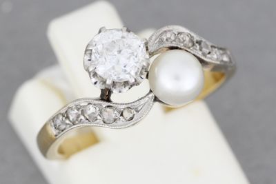 une photo d'une bague de fiançailles sertie d'un diamant et d'une perle, exposée dans une vitrine