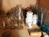 bottles and glasses on a shelf in a kitchen with a rolling pin