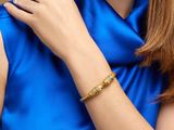 une femme qui porte une robe bleue et un bracelet doré
