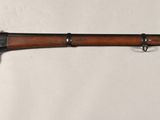 an old rifle mounted to a wall with a wooden handle
